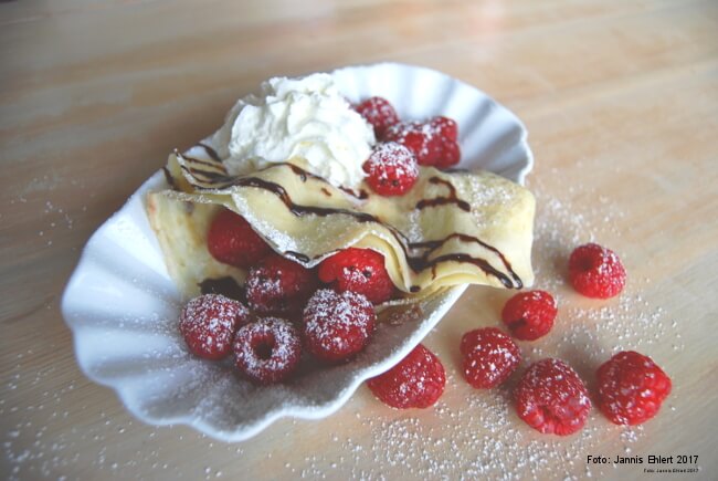 Leckere Crepes mit frischen Erdbeeren, Puderzucker und Schokoladensoße